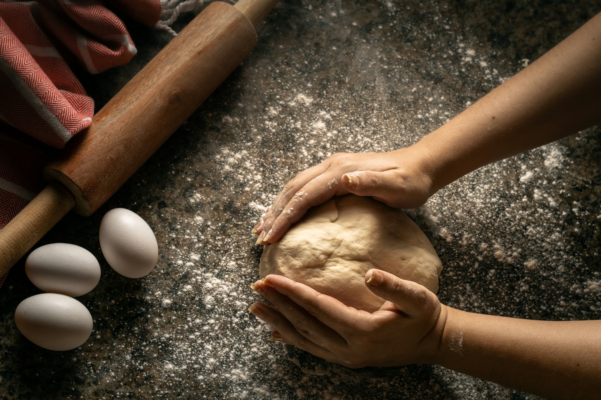Hands kneading dough on a floured surface